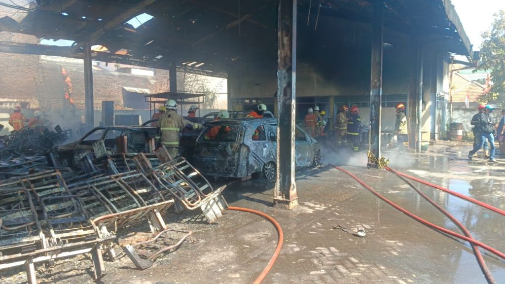 Petugas damkar melakukan pembasahan di Pool Damri di Surabaya yang terbakar (Foto: Kedaruratan 112 Surabaya)