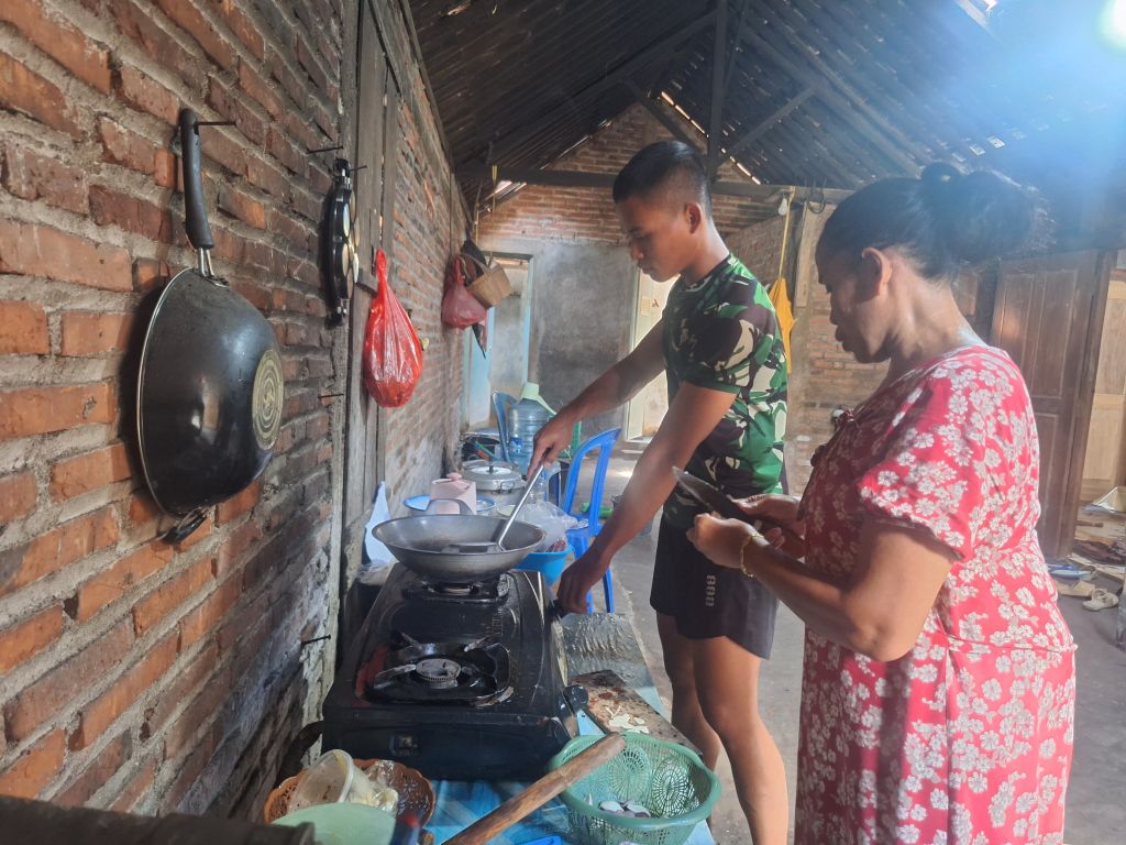 Anggota Satgas TMMD 128 Tak Canggung Bantu Ibu-Ibu Masak Di Dapur